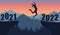 Silhouette of jumping girl over chasm between rocks on background of mountains with forest . Transition from 2021 to 2022, new