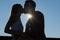 Silhouette of kissing couple against deep blue sky with sunbeams.