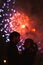 A silhouette of a kissing couple in front of a huge fireworks display.