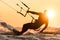 Silhouette of kitesurfer riding in sunset conditions with sun behind and lens flare