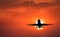 Silhouette of landing aircraft and red sky with sun