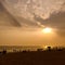 A silhouette landscape image of people watching sunset on a beach