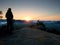 Silhouette of landscape photographer on peak above misty valley.