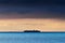 Silhouette of large container ship crossing Baltic sea under dramatic dark nimbostratus cloud formation.