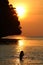 Silhouette little girl enjoy swimming and snorkeling near the beach with red sky and sunset