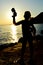 Silhouette of little girl with futuristic cyberpunk water pistol raised in left hand on rocky shore of Croatia.