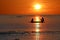 Silhouette of Local fishermen rowing small boats along the coast by the beach red sky sunset