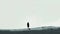 Silhouette of a lone person walking on a snowy landscape. Minimalist monochrome composition. Solitude and contemplation