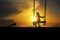 Silhouette of lonely girl with hijab on a swing with magical sunrise