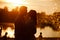 Silhouette of loving couple hugging on the lake at sunset. Beautiful young couple in love walking on the shore of the lake at