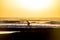 Silhouette of a male mountainbiker at sunset at the sea with wave for surfers in background - scenic place for sport adventure