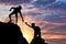 Silhouette of a male mountaineer giving a helping hand to his partner