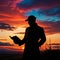 Silhouette of a male person reading book outdoors in sunset
