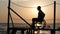 Silhouette of man with aching feet on wheelchair on pier enjoying sea sunset at summer travel