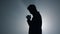 Silhouette man asking god blessing in darkness. Male person praying indoors.