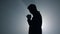Silhouette man asking god blessing in darkness. Male person praying indoors.