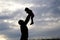 Silhouette of a man carrying a child.