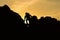 Silhouette of man climbing on rock mountain at sunset
