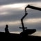 Silhouette of a man and crane against cloudy sky