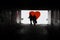 Silhouette of a man in a dark tonel against a background of a large red heart. Love, loneliness, conceptual photo.