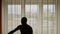 Silhouette of man doing Tai Chi at home in front of window. Morning asian practice. Locked indoors.