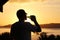 Silhouette of a man drinking beer at sunset