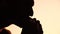 Silhouette of a man enjoying a hamburger. Side view portrait of a person savoring a delicious, satisfying burger with