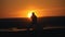 Silhouette of man fighter performing flips on the hill at summer sunset