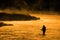 Silhouette of Man Flyfishing Fishing in River Golden Sunlight