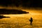 Silhouette of Man Flyfishing Fishing in River Golden Sunlight