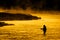 Silhouette of Man Flyfishing Fishing in River Golden Sunlight