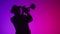 Silhouette of man in hat, playing musical trumpet and dancing. Studio, neon. Concept of jazz music, art and talent