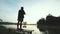 Silhouette of a man holding a fishing pole while standing alone fishing at the lake