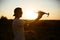 Silhouette of a man holding small compact drone and remote controller in his hands. Pilot launches quadcopter from his