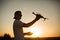 Silhouette of a man holding small compact drone and remote controller in his hands. Pilot launches quadcopter from his