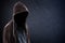 Silhouette of man with a hood, black background with copy space, criminal or hacker concept