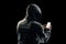Silhouette of a man in a hood on a black background, his face is not visible, the hacker is holding the phone in his hands. The