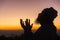 Silhouette of man kneeling down praying for worship God at sky background. Christians pray to jesus christ for calmness. In