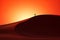 The silhouette of a man on a large dune in the desert against the background of the rising sun