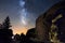 Silhouette of a man  in the night exploring a cave in the mountain with a torch under an amazing the milky way