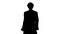 Silhouette Man in old-fashioned laced frock coat and white wig walking in a mannered way looking at camera.