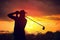 Silhouette of man playing golf at sunset