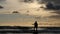 Silhouette of Man playing guitar on small rock in stormy sea - dolly shot