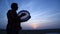 Silhouette of man plays the drum in sun set