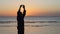 Silhouette of man practicing energy exercises at sunset by the sea