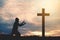 Silhouette man praying with cross