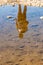 Silhouette of man reflecting in small puddle