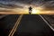 Silhouette of man riding motorcycle into sunset