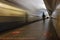 Silhouette of a man riding the push scooter on the platform of Shosse Entuziastov subway station with view of a leaving train. 