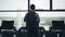 Silhouette of man running on the treadmill and looking into the large window. Medium distance of shot